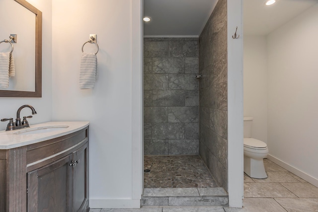 bathroom with tile patterned flooring, vanity, toilet, and tiled shower