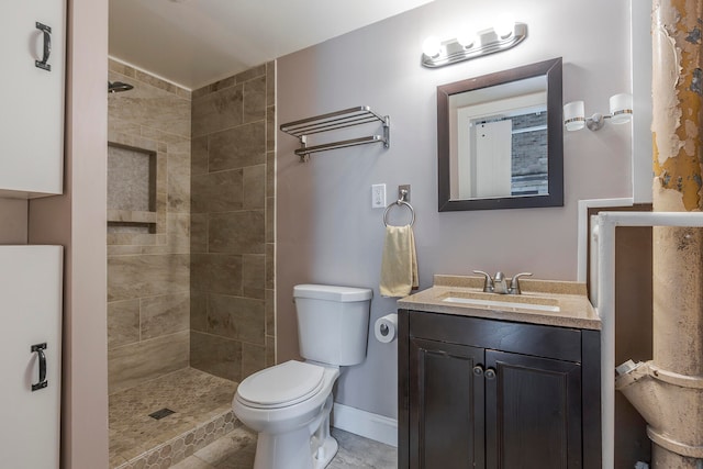 bathroom featuring toilet, vanity, tile patterned flooring, and tiled shower