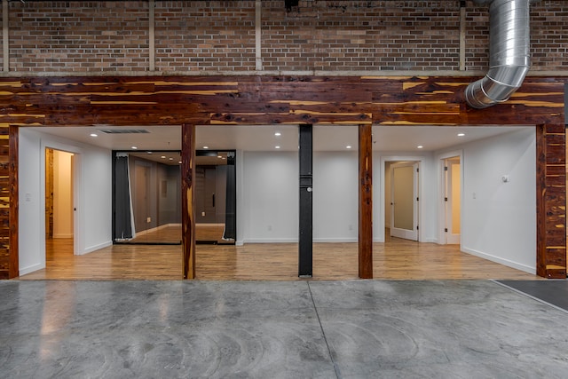 basement featuring hardwood / wood-style floors and brick wall