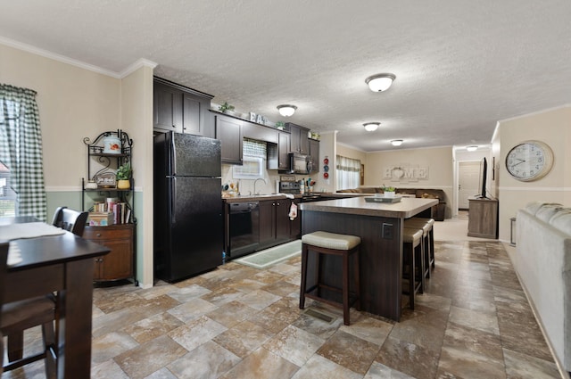 kitchen with a center island, dark brown cabinetry, black appliances, and a breakfast bar area