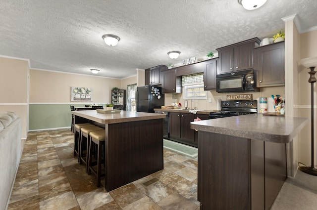 kitchen featuring crown molding, black appliances, a center island, and dark brown cabinets