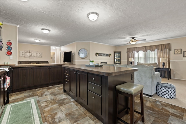 kitchen featuring a breakfast bar, a textured ceiling, dark brown cabinets, and ceiling fan