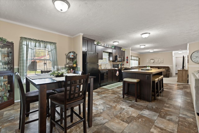 dining area featuring ornamental molding, sink, and a textured ceiling