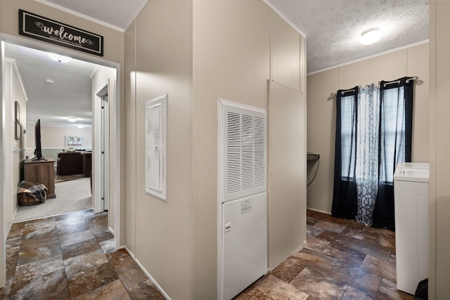 hall featuring ornamental molding, washer / clothes dryer, and a textured ceiling