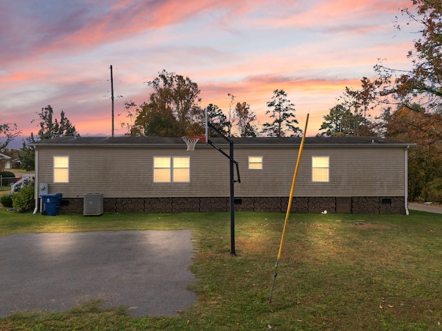 exterior space featuring central air condition unit and a lawn