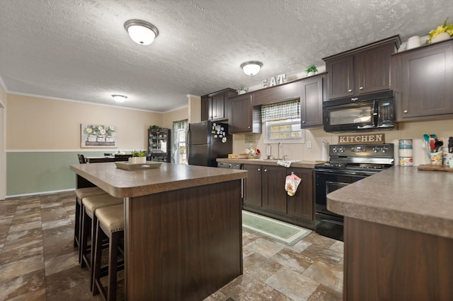 kitchen featuring a kitchen island, dark brown cabinets, black appliances, a breakfast bar, and a textured ceiling