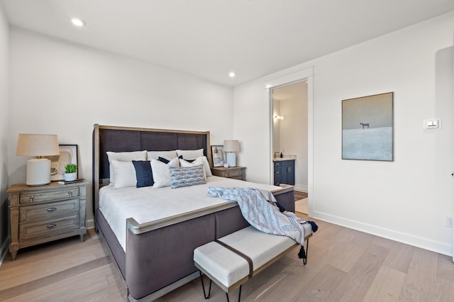 bedroom with ensuite bathroom and light hardwood / wood-style flooring