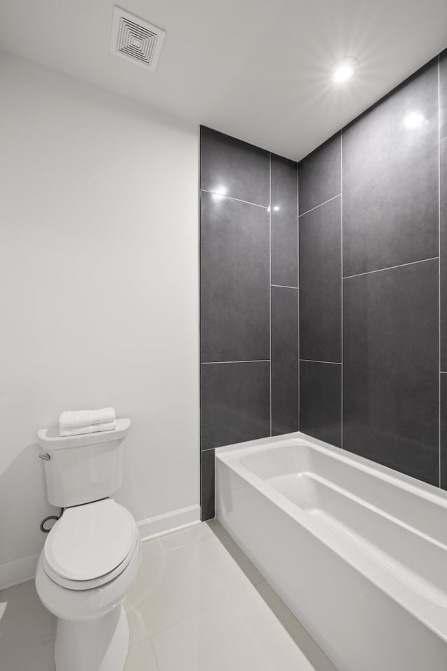 bathroom featuring tile patterned floors, toilet, and a bath