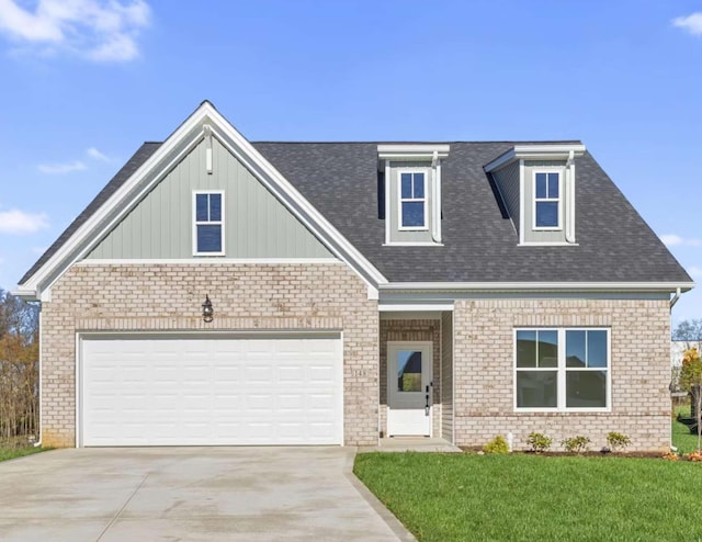 view of front facade with a garage, concrete driveway, roof with shingles, a front yard, and brick siding