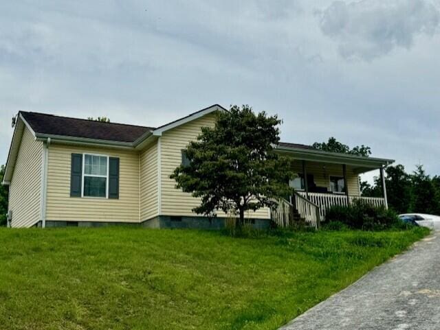 view of side of home featuring a yard and covered porch