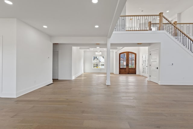 entryway with a chandelier, french doors, and light wood-type flooring