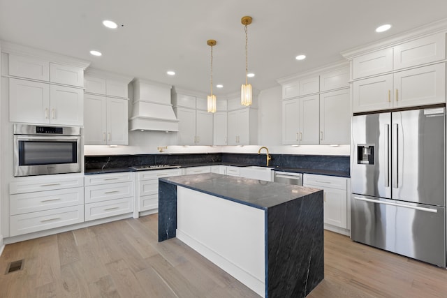 kitchen with custom exhaust hood, white cabinets, a kitchen island, pendant lighting, and stainless steel appliances