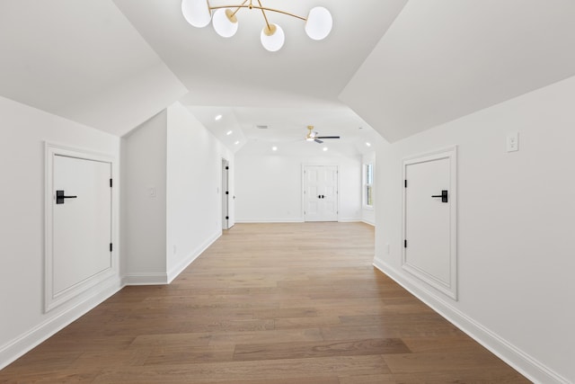 hallway featuring light hardwood / wood-style floors, lofted ceiling, and a chandelier