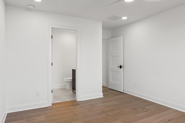 unfurnished bedroom with connected bathroom, light wood-type flooring, and ceiling fan