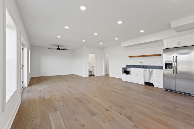 unfurnished living room featuring light hardwood / wood-style floors, indoor wet bar, and ceiling fan