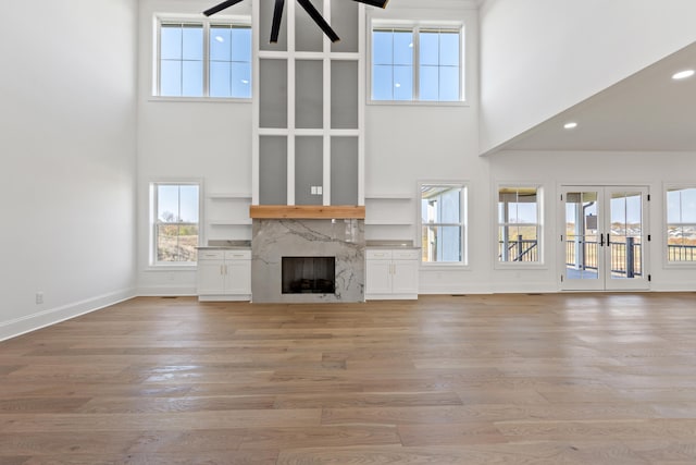 unfurnished living room featuring a premium fireplace, light wood-type flooring, and a wealth of natural light