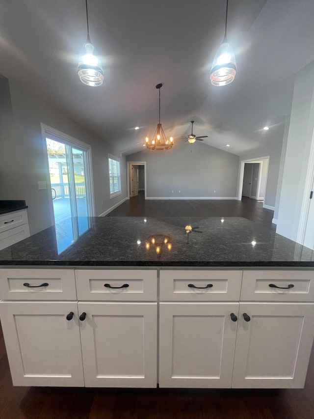 kitchen with dark stone countertops, vaulted ceiling, and white cabinets