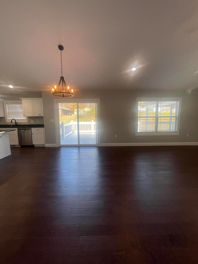 unfurnished living room with sink, an inviting chandelier, and dark hardwood / wood-style flooring