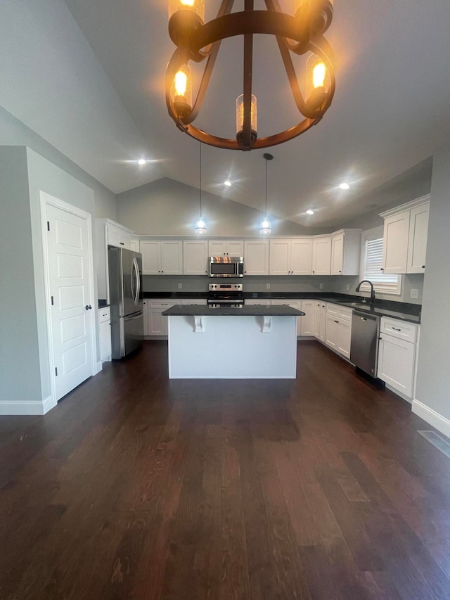 kitchen with white cabinets, hanging light fixtures, vaulted ceiling, dark wood-type flooring, and stainless steel appliances