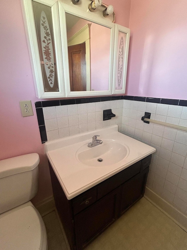 bathroom featuring vanity, toilet, and tile walls