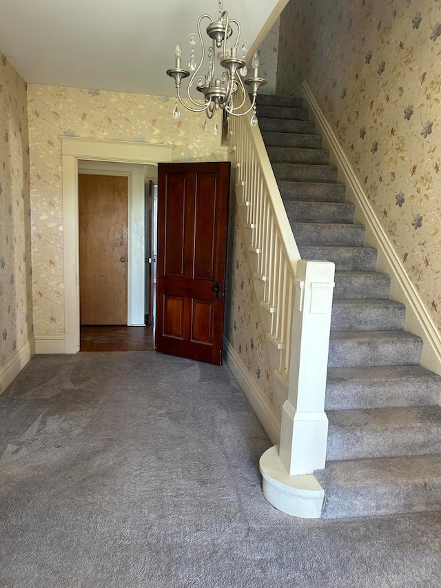 stairway featuring carpet flooring and a chandelier