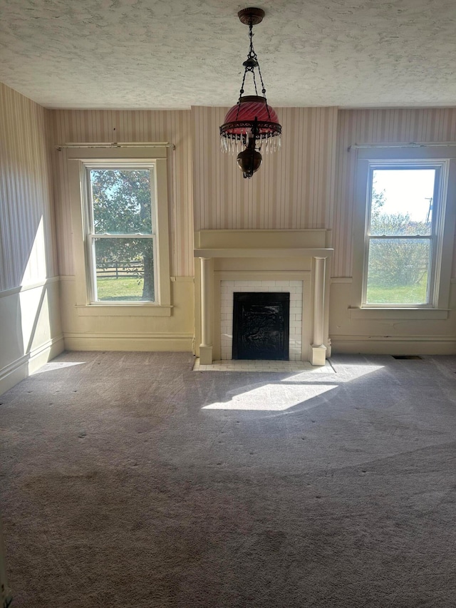 unfurnished living room featuring a healthy amount of sunlight, carpet, and a textured ceiling