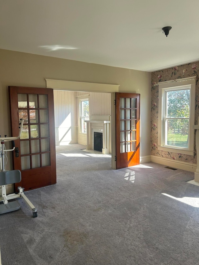 unfurnished living room featuring carpet and plenty of natural light