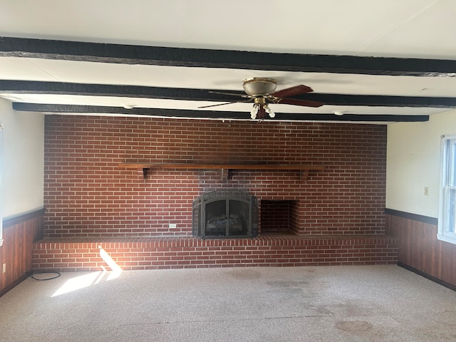 unfurnished living room featuring wood walls, carpet flooring, and a brick fireplace