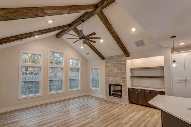 unfurnished living room with beamed ceiling, a fireplace, light wood-type flooring, and ceiling fan