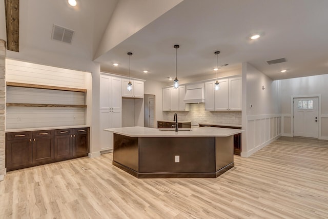 kitchen featuring light hardwood / wood-style floors, sink, premium range hood, and decorative light fixtures