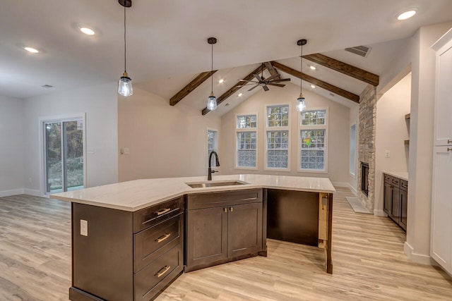 kitchen with a kitchen island with sink, sink, lofted ceiling with beams, light hardwood / wood-style floors, and ceiling fan