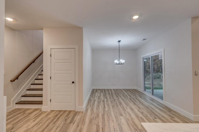 spare room featuring an inviting chandelier and light hardwood / wood-style flooring