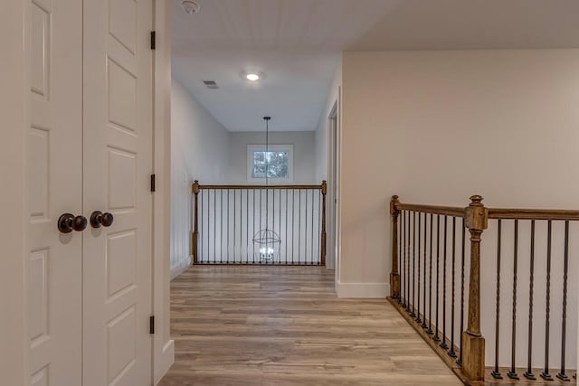 corridor with light hardwood / wood-style flooring and an inviting chandelier