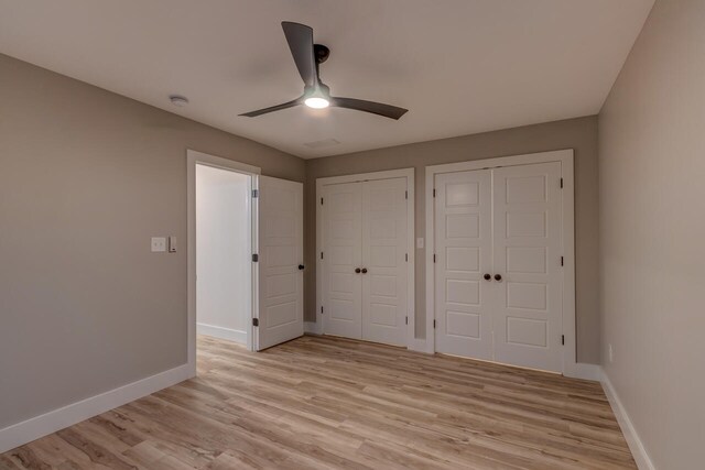 unfurnished bedroom with multiple closets, light hardwood / wood-style flooring, and ceiling fan