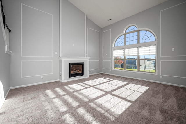 unfurnished living room featuring carpet floors and high vaulted ceiling