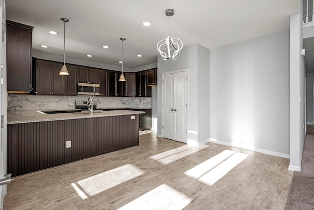 kitchen with kitchen peninsula, tasteful backsplash, dark brown cabinets, appliances with stainless steel finishes, and decorative light fixtures