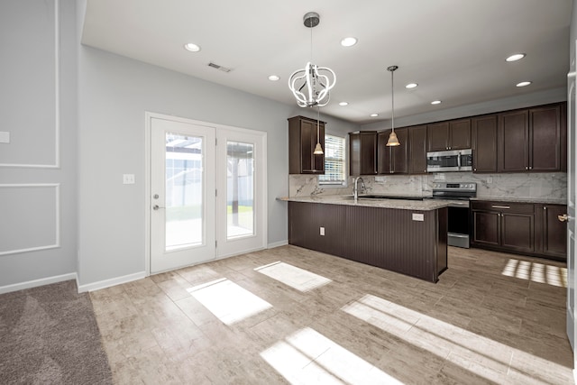 kitchen with kitchen peninsula, stainless steel appliances, light stone countertops, decorative light fixtures, and tasteful backsplash