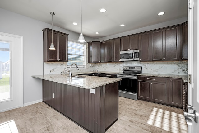 kitchen featuring kitchen peninsula, backsplash, sink, pendant lighting, and stainless steel appliances