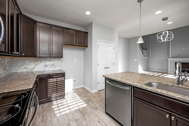 kitchen featuring light stone counters, appliances with stainless steel finishes, light hardwood / wood-style flooring, sink, and decorative light fixtures