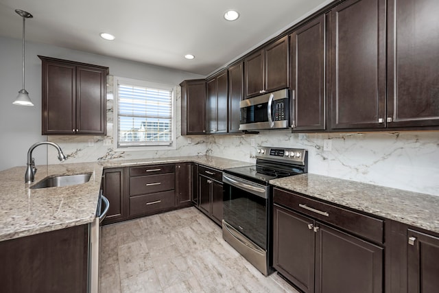 kitchen featuring hanging light fixtures, sink, appliances with stainless steel finishes, light hardwood / wood-style floors, and tasteful backsplash