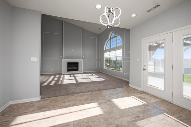 unfurnished living room featuring light colored carpet, a chandelier, and vaulted ceiling