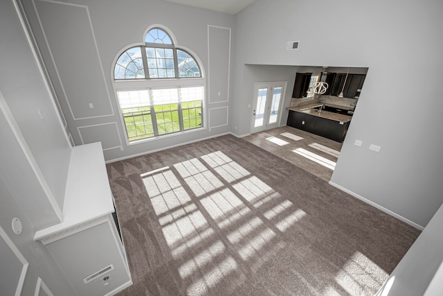 living room featuring a towering ceiling, french doors, and carpet floors