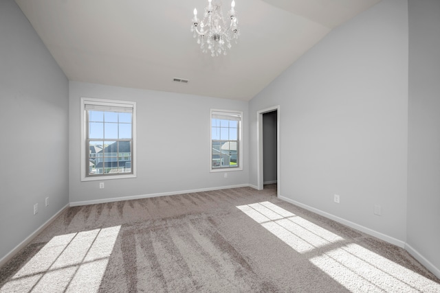 spare room featuring a notable chandelier, vaulted ceiling, and light colored carpet