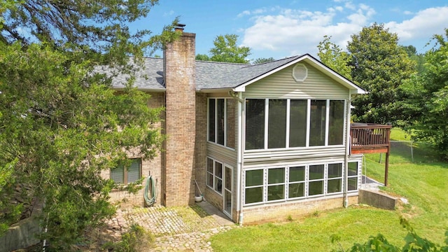 back of house featuring a sunroom and a lawn