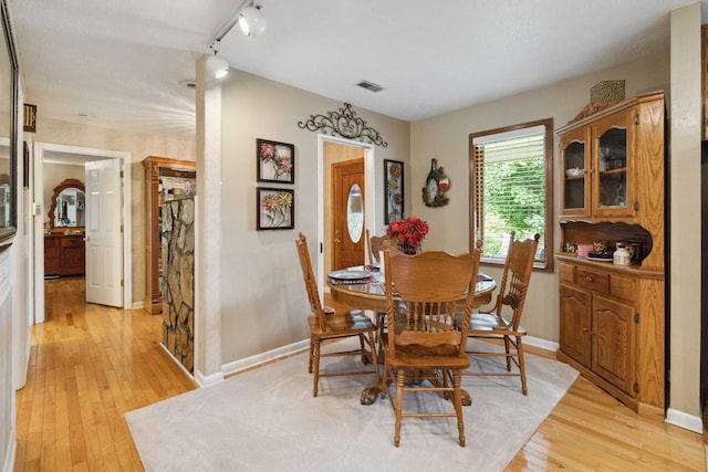 dining area with track lighting and light hardwood / wood-style flooring