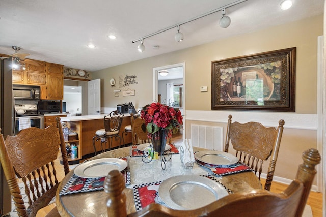 dining area featuring rail lighting and light hardwood / wood-style flooring