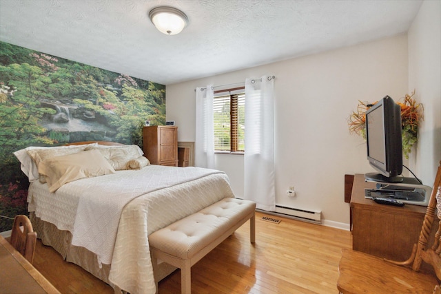 bedroom featuring light hardwood / wood-style flooring, a textured ceiling, and baseboard heating