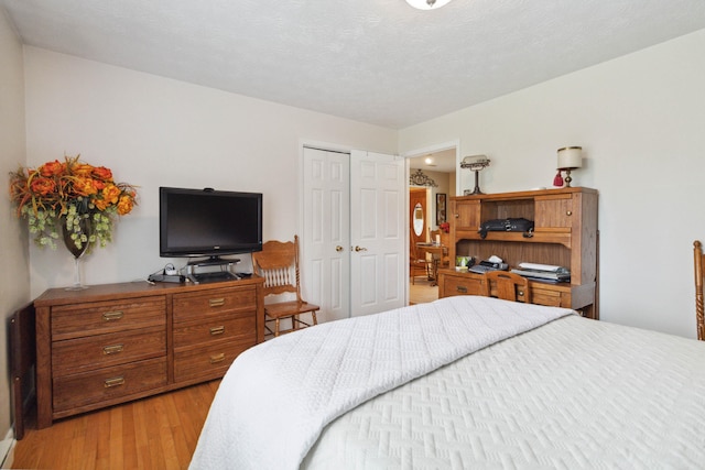 bedroom featuring a closet, a textured ceiling, and light hardwood / wood-style floors