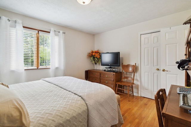 bedroom with light hardwood / wood-style floors and a textured ceiling