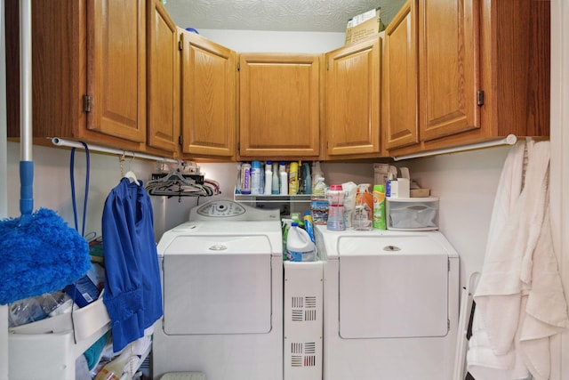 washroom featuring a textured ceiling, washing machine and dryer, and cabinets